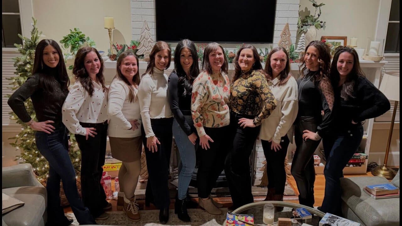 Quinnipiac alumna Kimberly Saccucci posing for a picture in a living room with several friends from Quinnipiac