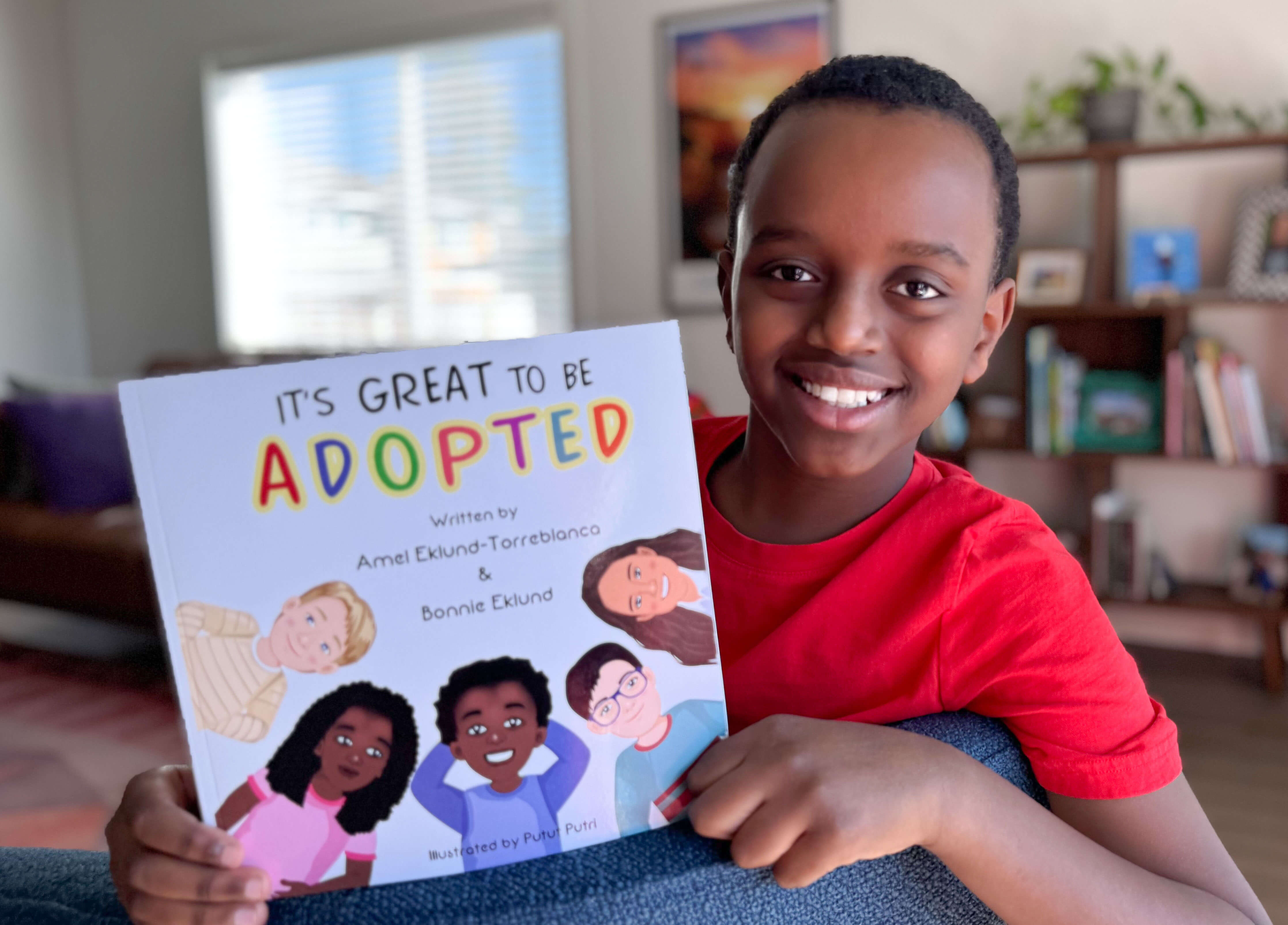 Amel Eklund-Torreblanca holds the book "It's Great to be Adopted"