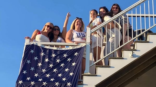 Quinnipiac alumna Bryanna Paternostro poses for a picture with classmates on a boat with the American flag