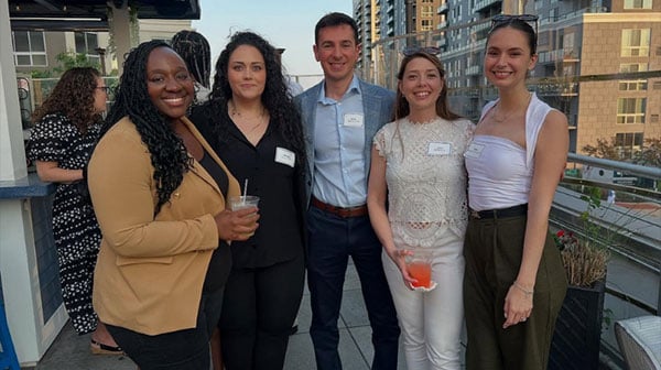 Quinnipiac alumni posing for a picture at a rooftop event.