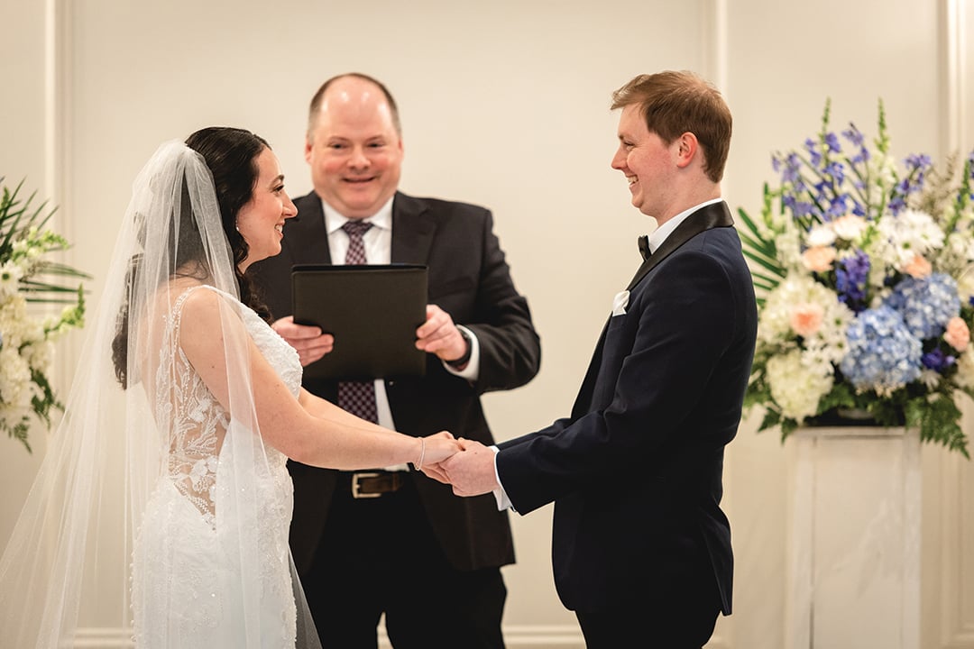 Meghan and Connor Aikens-Kinney hold hands while Justin Kile presides on a wedding alter