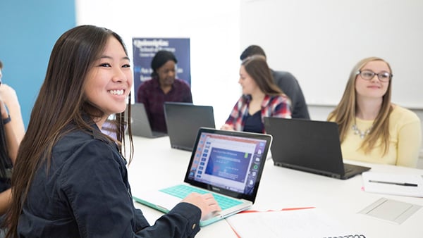 Students work on laptops in a classroom