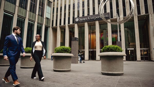 2 students walking in NYC out front of the New Corporation building